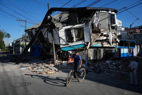 A neighbor rides past damaged homes a day after an earthquake struck Pereira, Colombia, Tuesday, Aug. 11, 2026. (AP Photo/Fernando Vergara)