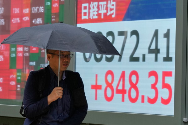 A person walks in front of an electronic stock chart board showing Japan's Nikkei index at a securities firm Thursday, Aug. 13, 2026, in Tokyo. (AP Photo/Eugene Hoshiko)