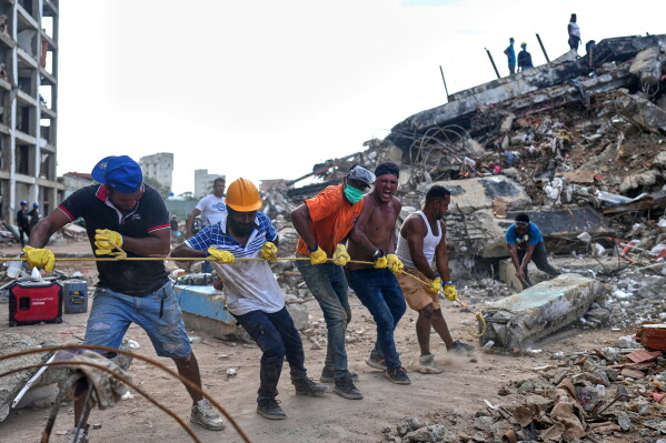 Volunteers pull a rope to remove a debris from a collapsed building by earthquakes in La Guaira, Venezuela, Sunday, July 12, 2026. (AP Photo/Ariana Cubillos)