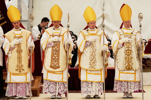 Newly consecrated bishops, from left, Marc Hanappier, Michel Poinsinet de Sivry, Michael Goldade and Pascal Schreiber wearing their miters and holding their pastoral staffs, stand at the end of their consecration ceremony in a tent set up outside the Society of St. Pius X seminary in Econe, Switzerland, Wednesday, July 1, 2026. (AP Photo/Baz Ratner)