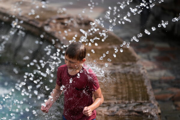 A boy cools himself off in a fountain on a hot summer day in Moscow, Thursday, Aug. 6, 2026. (AP Photo/Pavel Bednyakov)