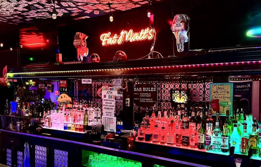 A dark, but colorfully lit bar at Fat Matt's Vortex, with skulls above the bar.