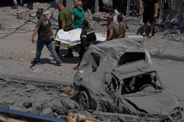 Rescue workers carry a plastic bag, containing the body of a person who was killed at a house that was hit by an Israeli airstrike in Deir al-Zahrani village, southern Lebanon, Saturday, Aug. 15, 2026. (AP Photo/Mohammed Zaatari)