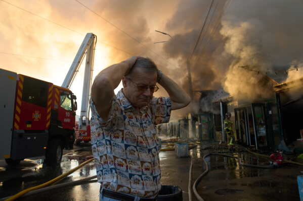Bookseller Alexander Bahlai reacts as firefighters try to put out a fire at a city book market following a Russian missile attack in Kyiv, early Sunday, Aug. 16, 2026. (AP Photo/Francisco Seco)