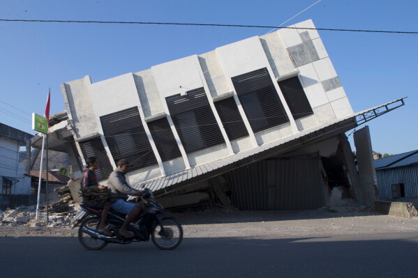 Motorists ride past a building that collapsed during an earthquake in Reo, East Nusa Tenggara province, Indonesia, Monday, Aug. 17, 2026. (AP Photo/Firdia Lisnawati)