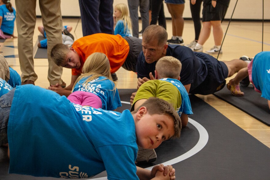 Kids at the Newton YMCA work on their planking technique. They rotated to different stations in the gymnasium to learn about some of the exercises in the presidential fitness test.