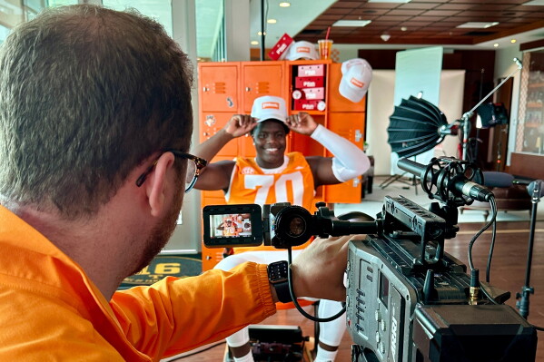 Tennessee left tackle David Sanders Jr. smiles while filming videos with Isaac Fowler, a Learfield Studios supervising producer, for Sanders' NIL deal during Learfield's NIL media content production day with the university in Knoxville, Tenn., July 23, 2026. (AP Photo/Teresa M. Walker)
