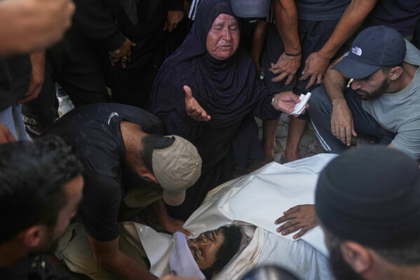Relatives and friends grieve over the body of Hassan Qahman at a hospital morgue after he was killed in an Israeli airstrike in Gaza City, Saturday, Aug. 1, 2026. (AP Photo/Jehad Alshrafi)