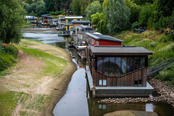Houseboats sit in low water on the Waal river in Nijmegen, Netherlands, Thursday, July 30, 2026, due to drought conditions. (AP Photo/Patrick Post)