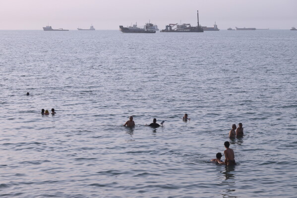 Residents swim as cargo and commercial vessels are anchored in the Strait of Hormuz off Bandar Abbas, Iran, Thursday, Aug. 6, 2026. (Amirhosein Khorgooi/ISNA via AP)