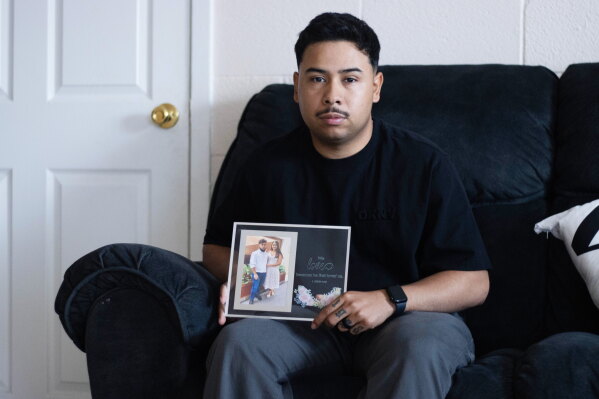 Army Sgt. Hedar Leonel Turcios Juarez holds a picture of himself with with his wife Cristy at home in El Paso, Texas, July 21, 2026. (AP Photo/Ryan Romero, File)