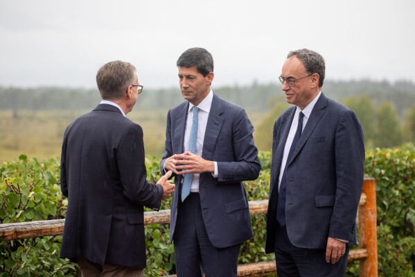 Fed Chair Kevin Warsh, center, talks to Bank of England Governor Andrew Bailey, right, and Bank of Canada Governor Tiff Macklem at the annual Jackson Hole Economic Policy Symposium on Friday, Aug. 28, 2026, in Moran, Wyo. (AP Photo/Amber Baesler)
