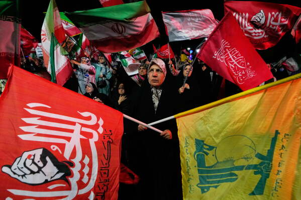 Pro-government demonstrators wave flags including a flag of Lebanon's militant Hezbollah group, right, during a gathering in a square in Tehran, Wednesday, Aug. 26, 2026. (AP Photo/Vahid Salemi)
