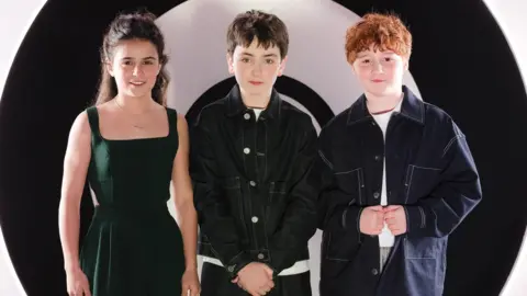 David Jon/HBO Max Arabella Stanton, Dominic McLaughlin and Alastair Stout standing together ina promotional photo and not in costume