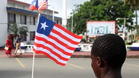 EPA A back view of person holding a small Liberian flag on a street in Monrovia