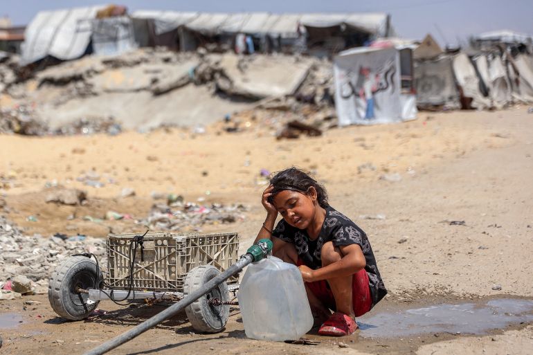 A girl fills containers with water drawn from the leftovers of underground pipes at a camp for people displaced by war in the Sheikh Radwan neighbourhood of Gaza City on July 6, 2026. The Palestinian Islamist movement Hamas announced on July 6 the dissolution of the body that has governed the Gaza Strip for nearly two decades, clearing the way for a technocratic committee to implement civilian rule. Since a ceasefire took effect in Gaza last October between Hamas and Israel, the group has repeatedly said it is prepared to step aside from day-to-day governance, but the thorny issue of its disarmament remains unresolved. (Photo by Omar AL-QATTAA / AFP)