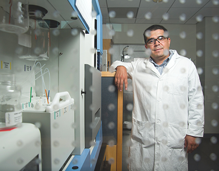 Portrait of genomic researcher Luis Carvajal-Carmona standing in a lab and wearing a white coat