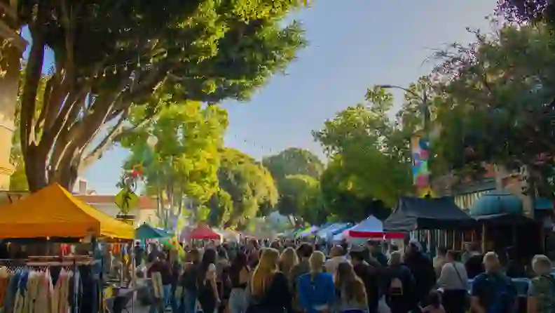 Crowded street lined with market tents at dusk
