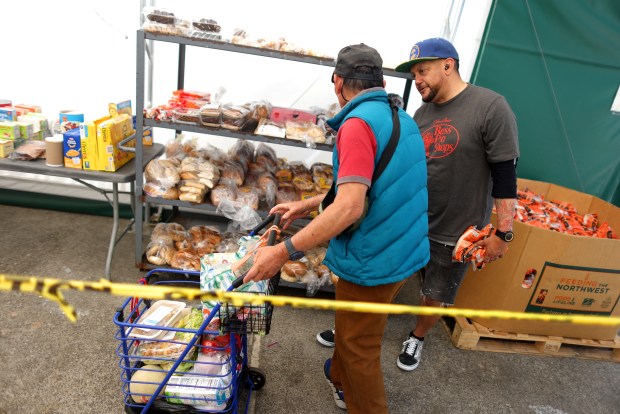 Volunteer Chris Ibarra, right, helps to distribute food to community members at the South Hayward Parish Food Pantry on Tuesday, Aug. 11, 2026 in Hayward, Calif. After years of operation as both a food pantry and homeless shelter, First Presbyterian Church of Hayward has decided to close the food pantry effective Friday 14th of August. (Aric Crabb/Bay Area News Group)