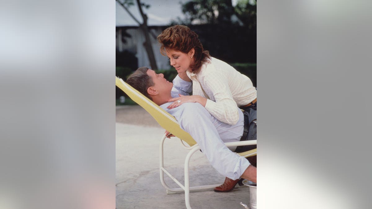 Linda Gray leans over Larry Hagman in a promotional scene from the television series Dallas.
