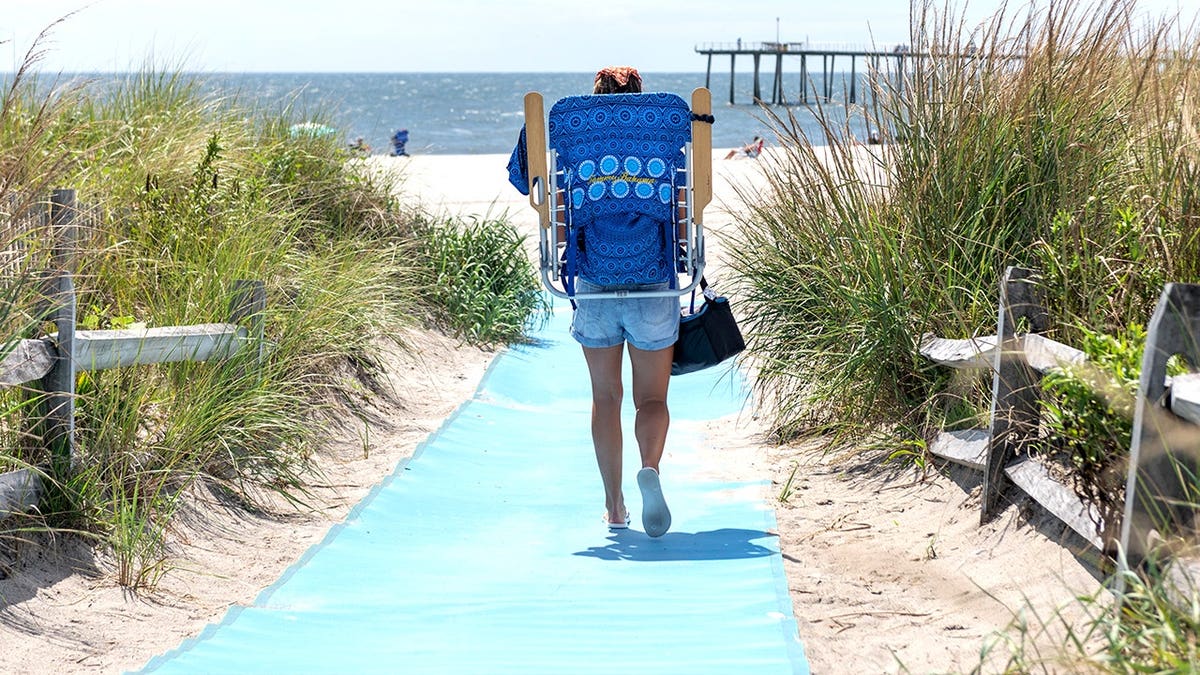 Woman walking to NJ beach with beach chair