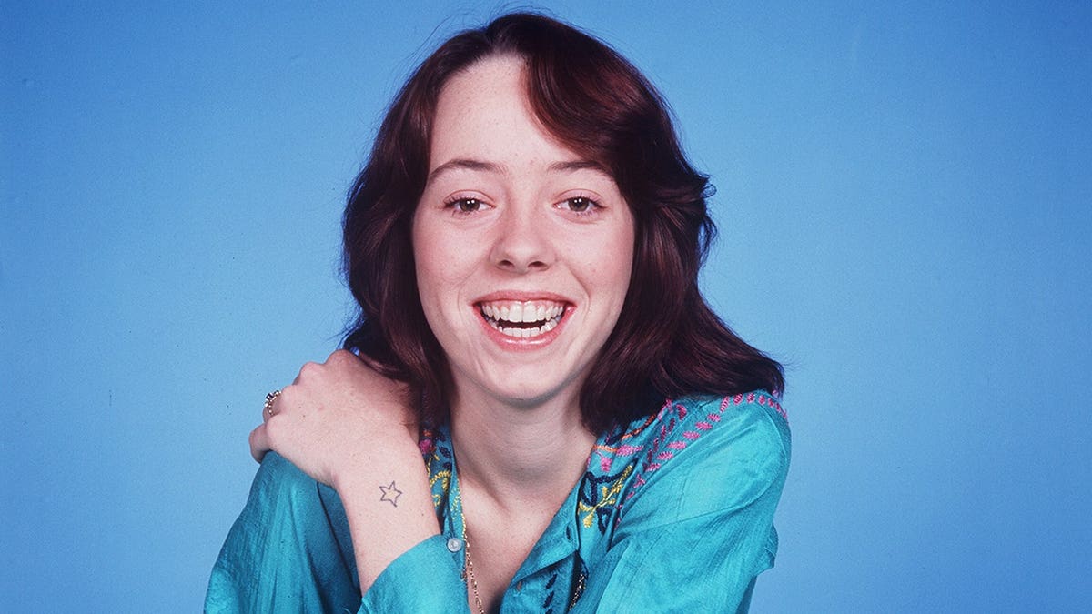 Mackenzie Phillips stands as Julie Cooper in a studio portrait.