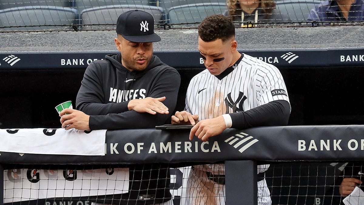 Giancarlo Stanton and Aaron Judge look at an iPad at Yankee Stadium.