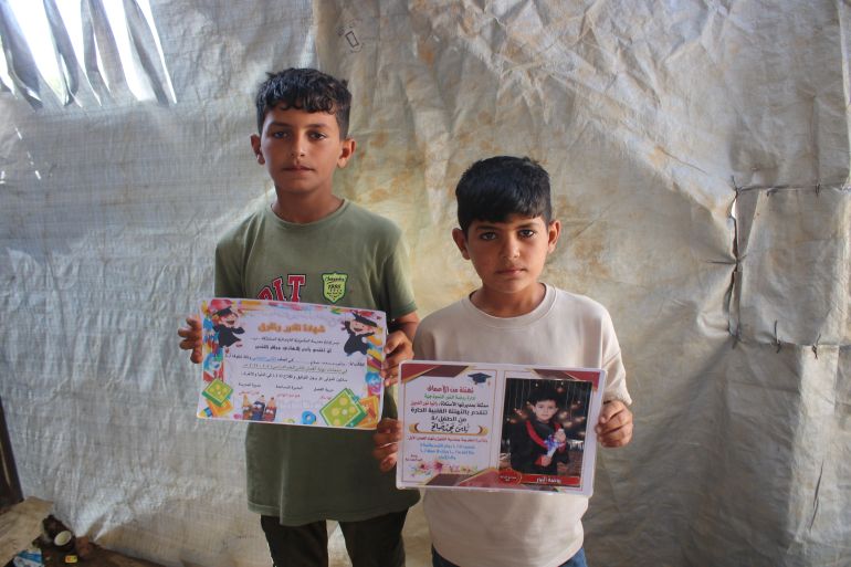 Yamen and Aman Saleh display their school certificates, in Maghazi, Gaza