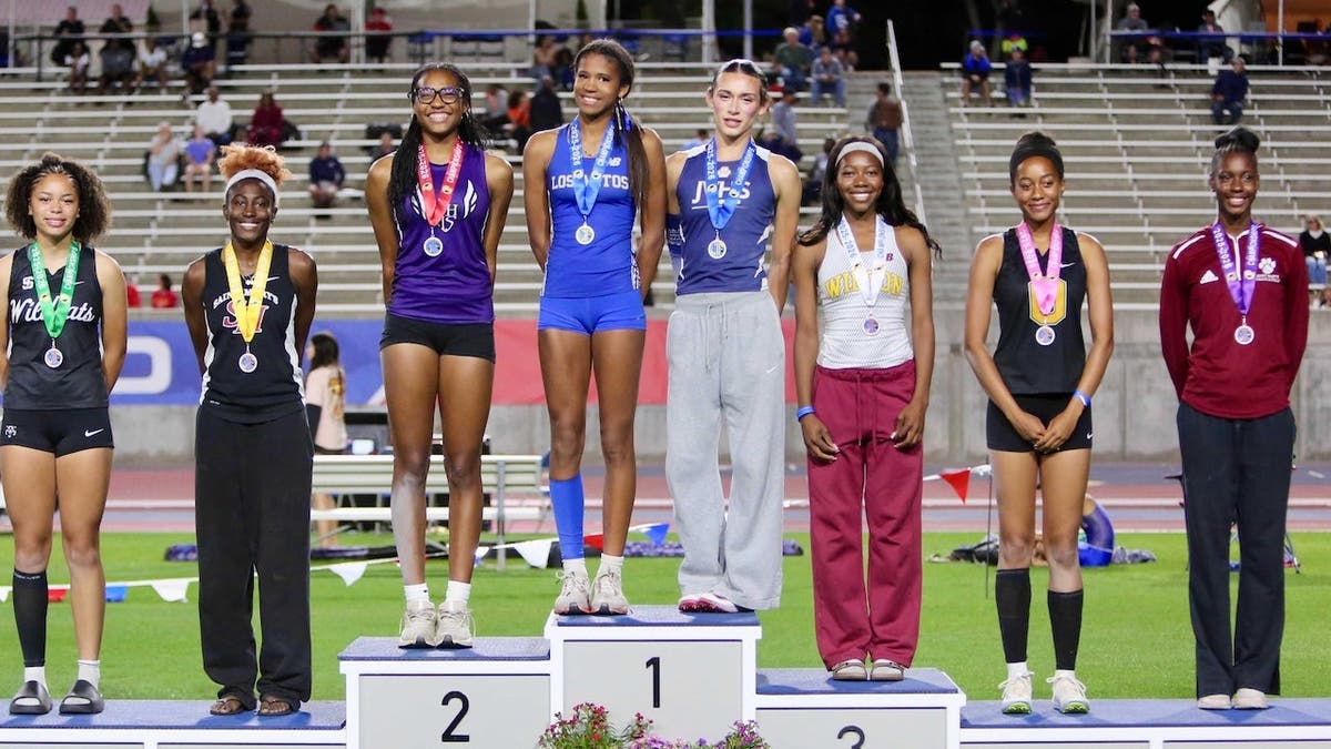 AB Hernandez stands on the first-place podium alongside a female oppponent at the 2026 California track and field state championships. It was a flashpoint in the history of girls' sports.