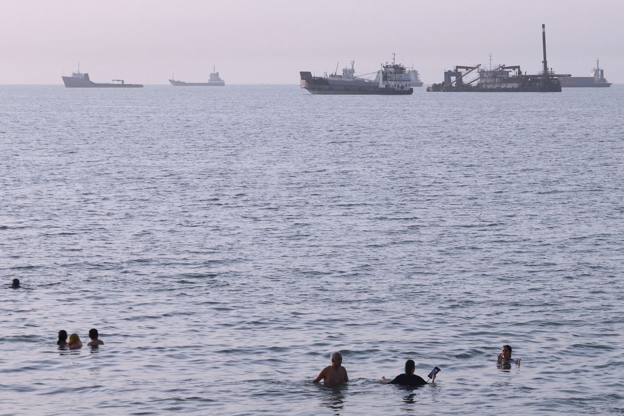 Residents swim as cargo and commercial vessels are anchored in the Strait of Hormuz off Bandar Abbas, Iran, on Thursday.