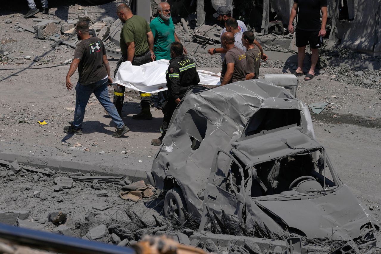 Rescue workers carry the body of a person who was killed by an Israeli airstrike in Deir al-Zahrani, Lebanon on Saturday.