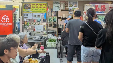 BBC People line up at nearby shop at the food centre on Monday