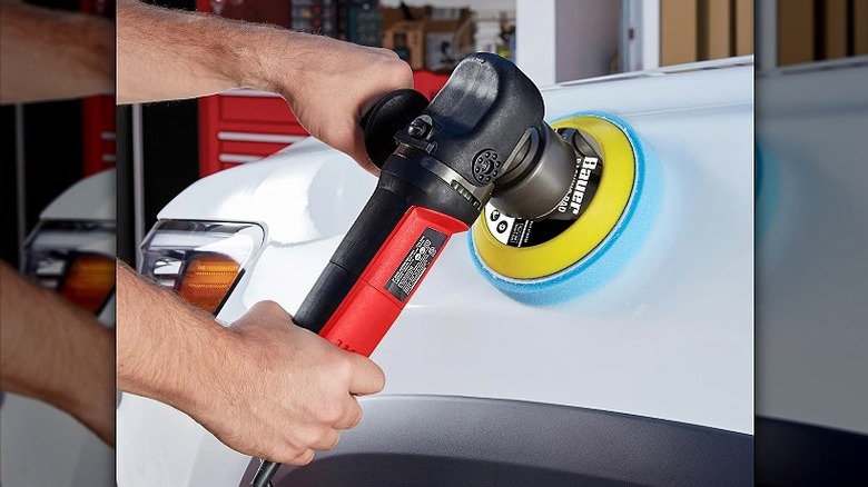 Using an orbit sander on a white vehicle.