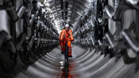 National Grid An engineer in a high-viz jacket cycles down a Power Tunnel under London.