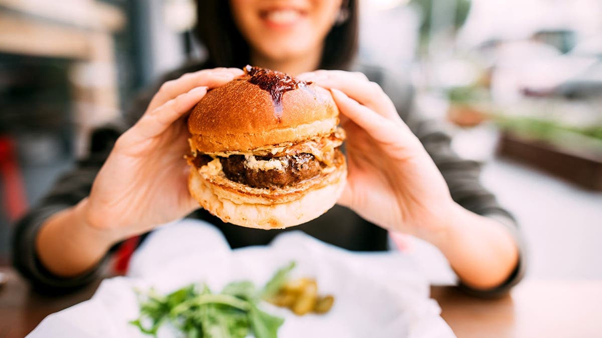 A woman holds a burger.