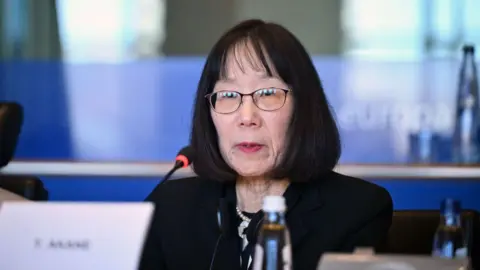 Getty Images Judge Tomoko Akane  at the microphone at an event in Brussels