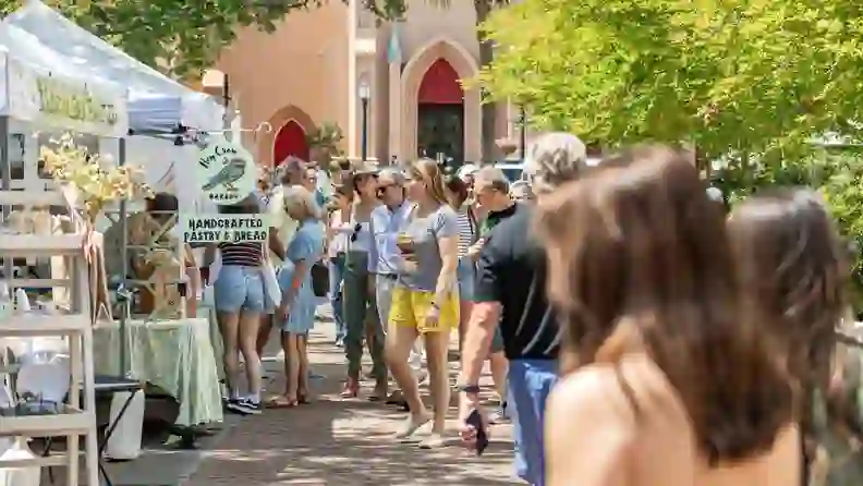 Crowd walking past a bakery stall at an outdoor market