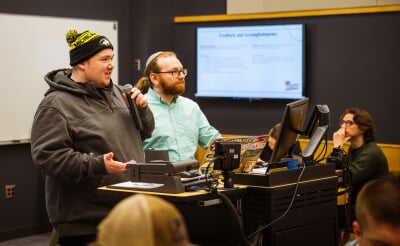 Two students presenting in front of a projection screen.