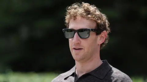 Reuters A close-up of Mark Zuckerberg, wearing a set of Meta Ray-Bans and brown top, walking through a park.