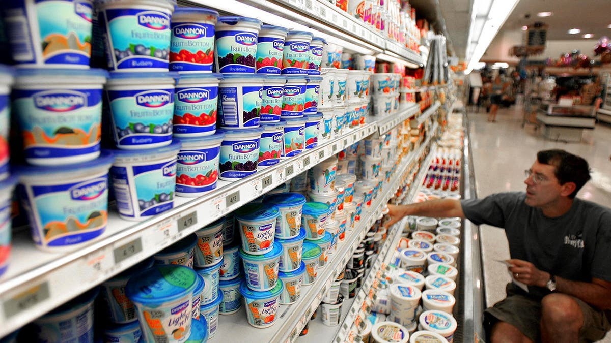 A man shops for yogrut at a supermarket.