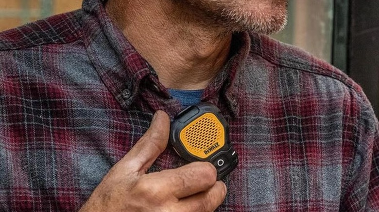 A DeWalt mini speaker clipped onto a person's shirt
