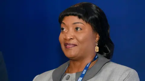 NurPhoto via Getty Images Jewel Howard-Taylor wears a blue lanyard and grey jacket, gold earring at an economic forum in Poland, 2021. She has shiny black hair.
