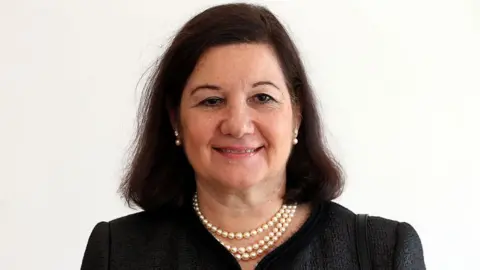AFP via Getty Images A head and shoulders shot of a woman with dark, shoulder-length hair wearing a dark top and a pearl necklace