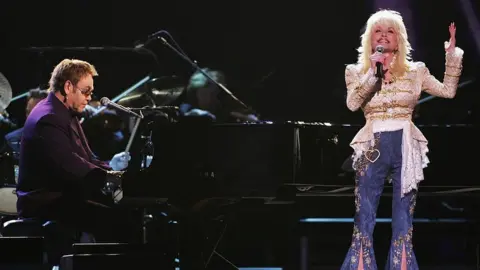 Getty Images Elton John and Dolly Parton perform "Turn the Lights Out When You Leave" and "Imagine" (Photo by Michael Loccisano/FilmMagic for Country Music Association)