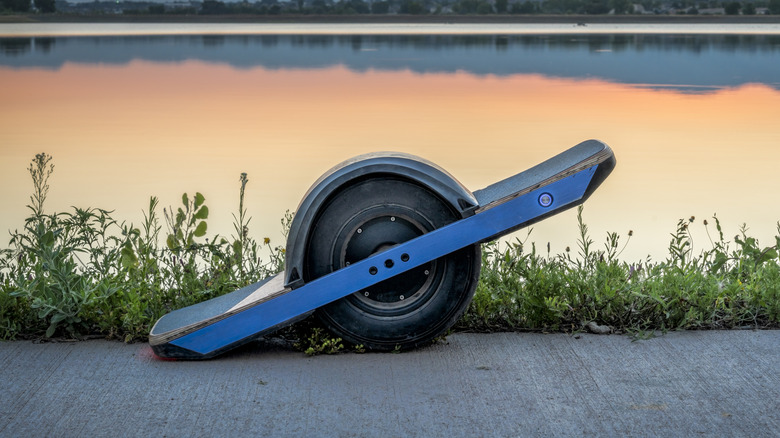A Onewheel electric self-balancing skateboard parked along a waterfront path.