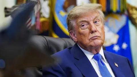 Bloomberg via Getty Images Donald Trump glances to his right while seated at his desk in the Oval Office.