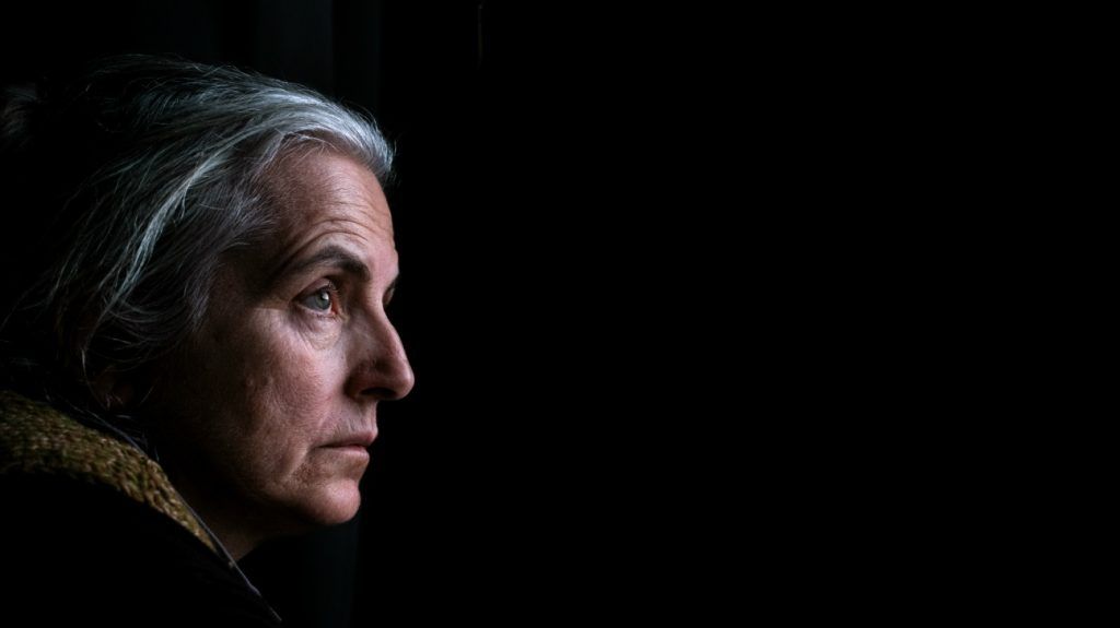 side profile of older white woman on dark profile