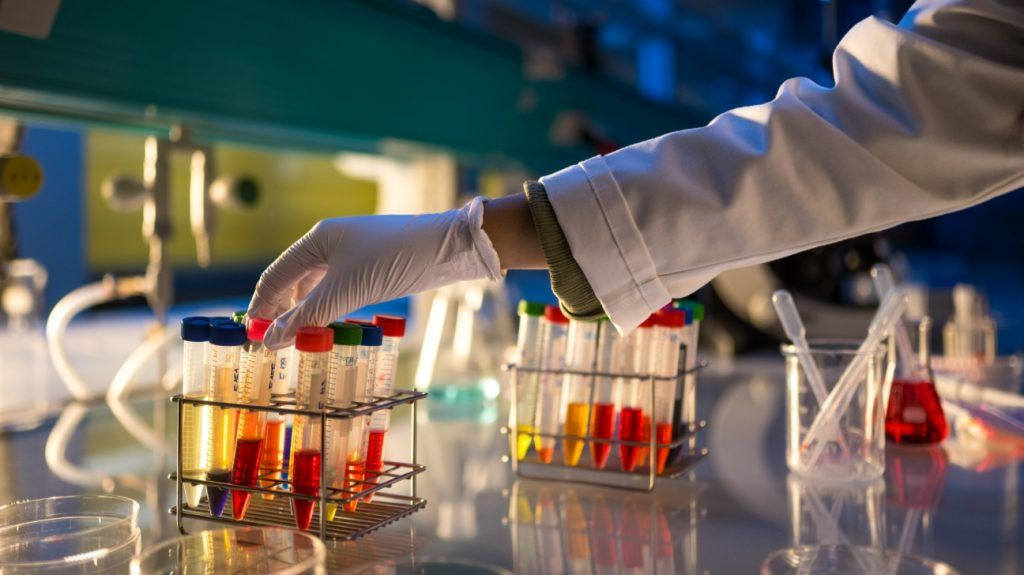 gloved hand adjusting test tubes in laboratory