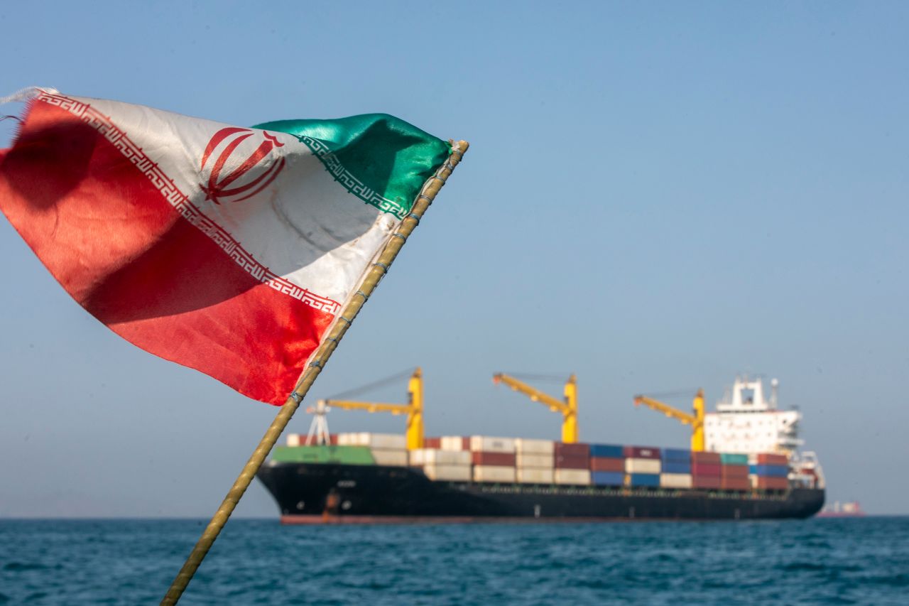 An Iranian flag flutters in the wind as ships are anchored in the Strait of Hormuz near Larak Island, Iran, on May 16.