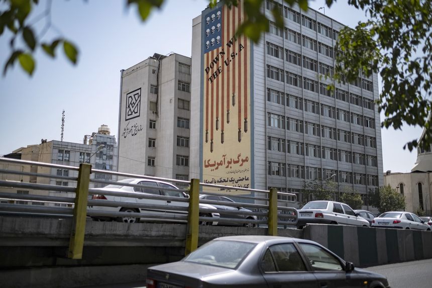 Vehicles move along an avenue beneath an anti-U.S. mural in Tehran, Iran, on July 16, 2026. This occurs amid new tensions between Iran and the United States.